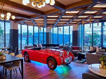 A room with a red convertible car in the middle of it